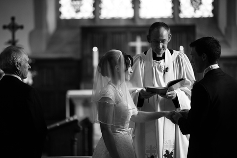 wedding in church with bride, groom and father of the bride at altar with vicar