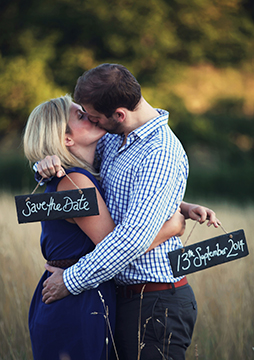 Couple standing in a field holding Save the Date signs